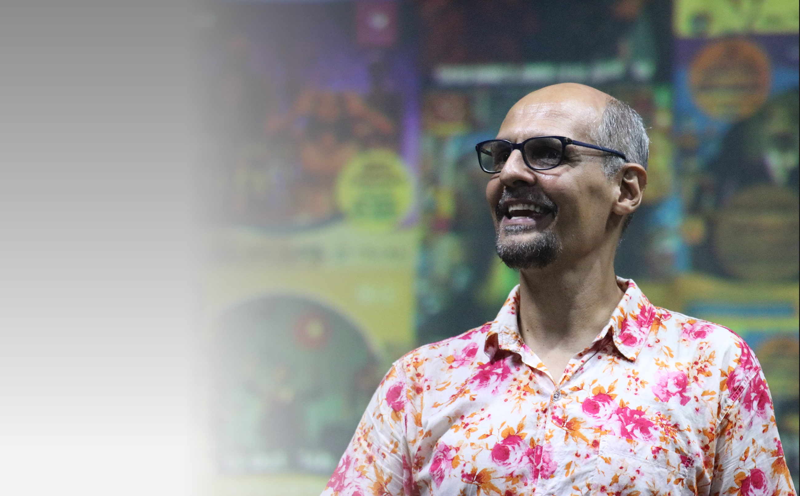 Leidson Ferraz sorrindo diante de cartazes de teatro
